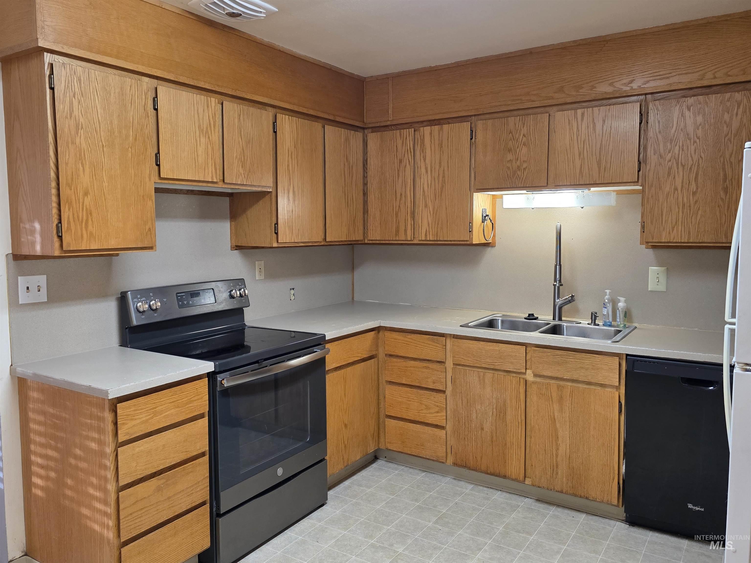 Kitchen with electric stove, dishwasher, light countertops, light floors, and brown cabinets