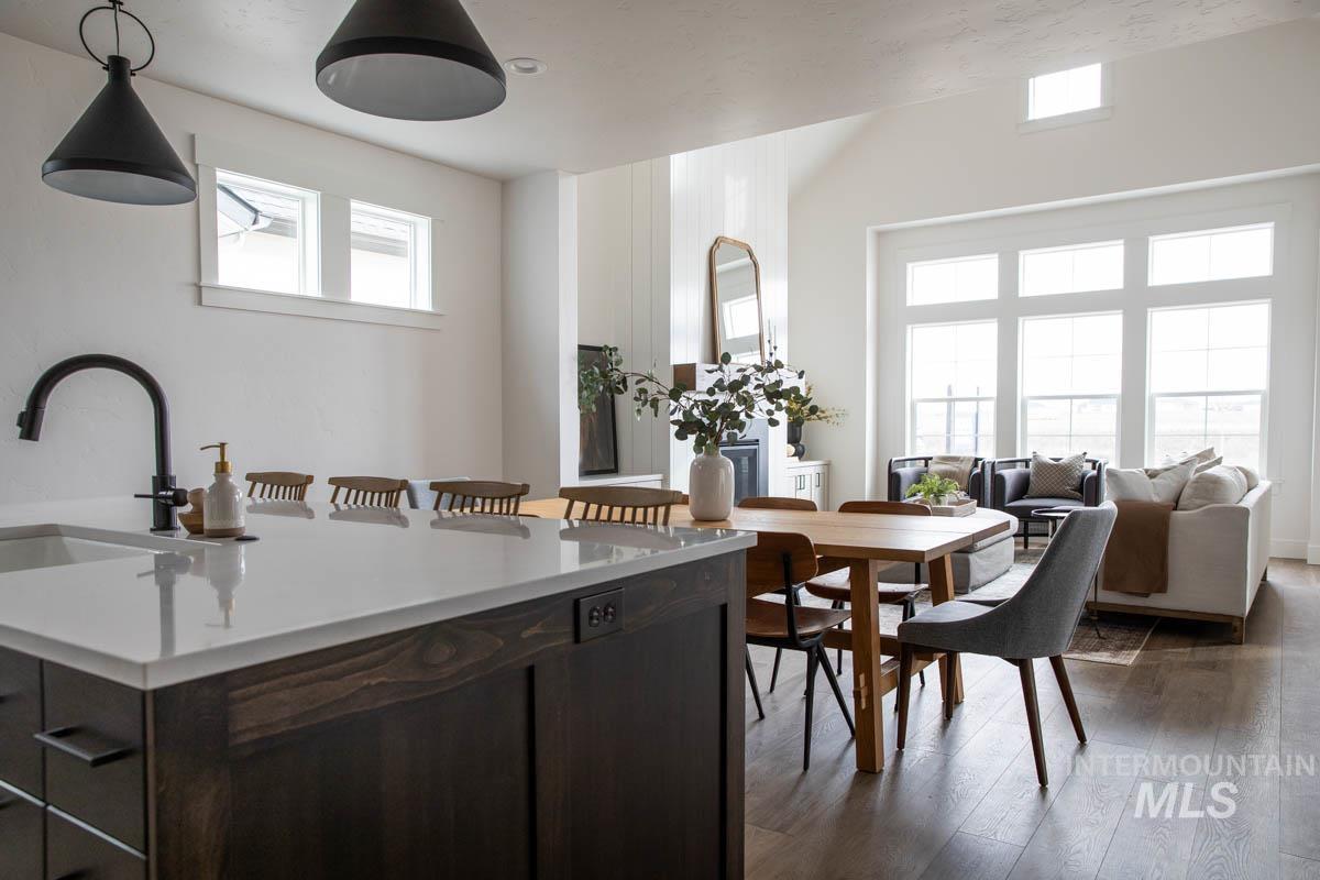 Kitchen with dark brown cabinetry, a breakfast bar area, dark wood-type flooring, and decorative light fixtures