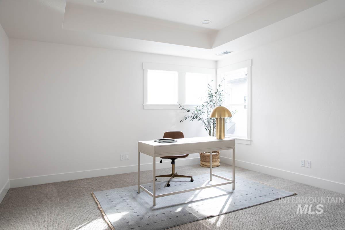 Home office with a tray ceiling, light colored carpet, and recessed lighting