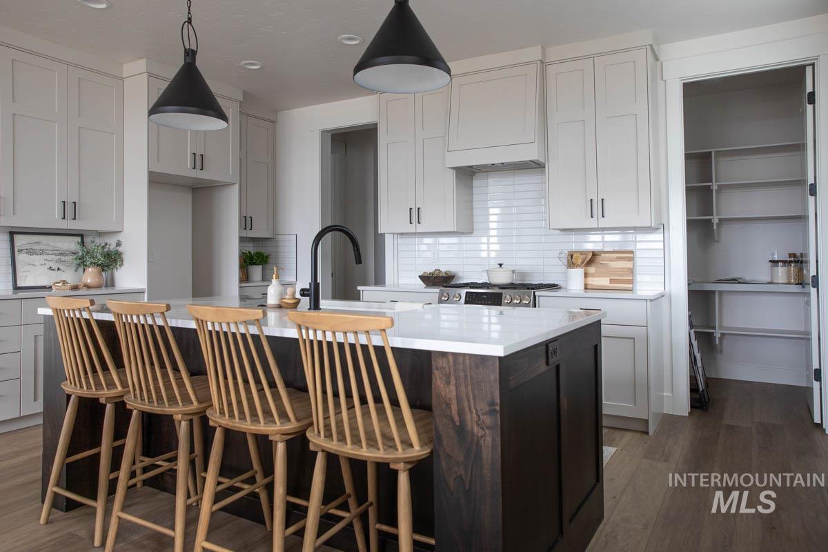Kitchen featuring a kitchen island with sink, dark wood-style flooring, decorative light fixtures, tasteful backsplash, and recessed lighting