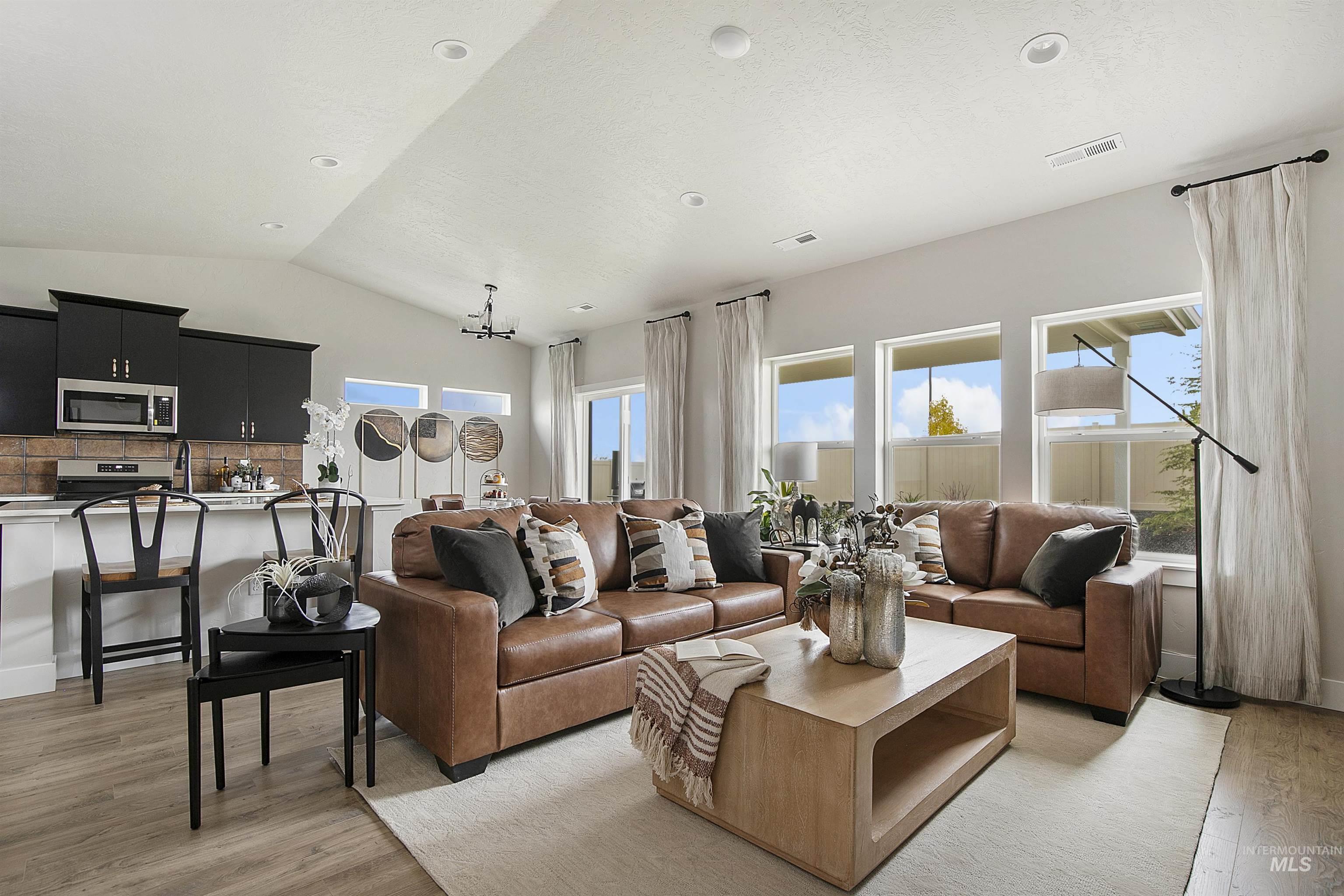 Living area featuring plenty of natural light, light wood-type flooring, lofted ceiling, and recessed lighting