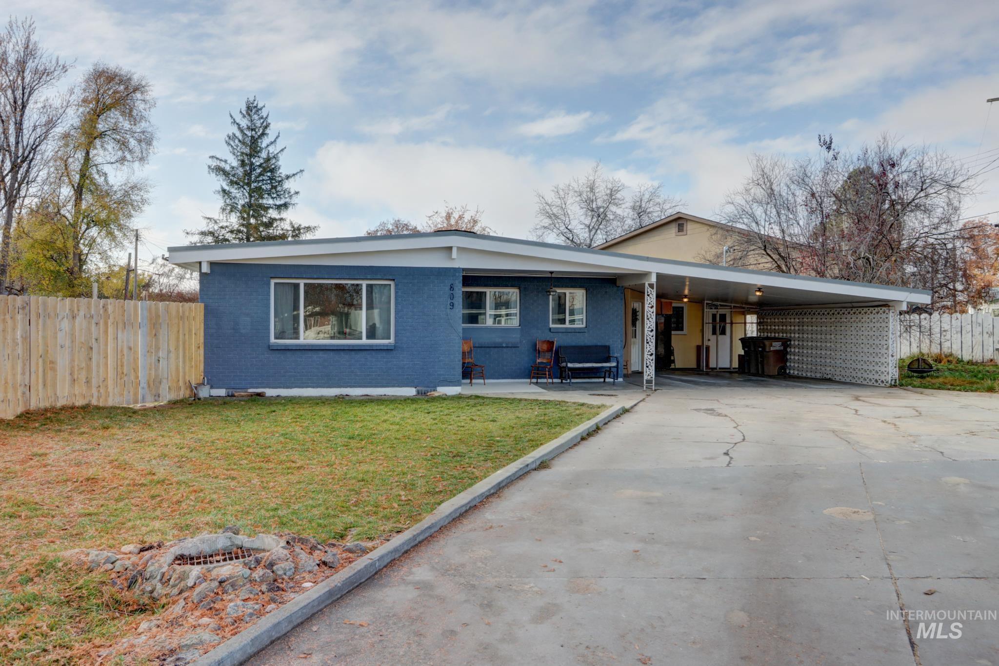 View of front of home with concrete driveway, a carport, brick siding, and a patio area