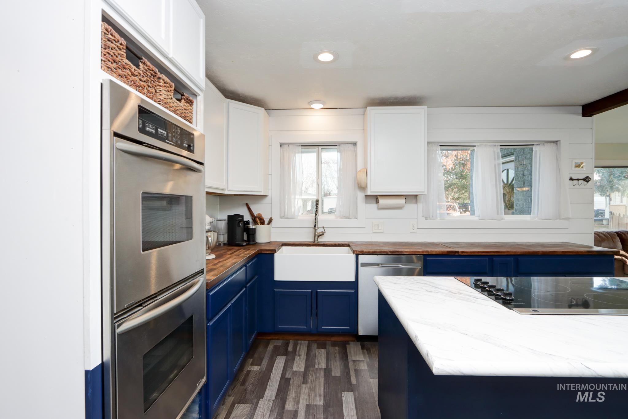 Kitchen featuring blue cabinets, appliances with stainless steel finishes, wooden counters, recessed lighting, and dark wood-style flooring
