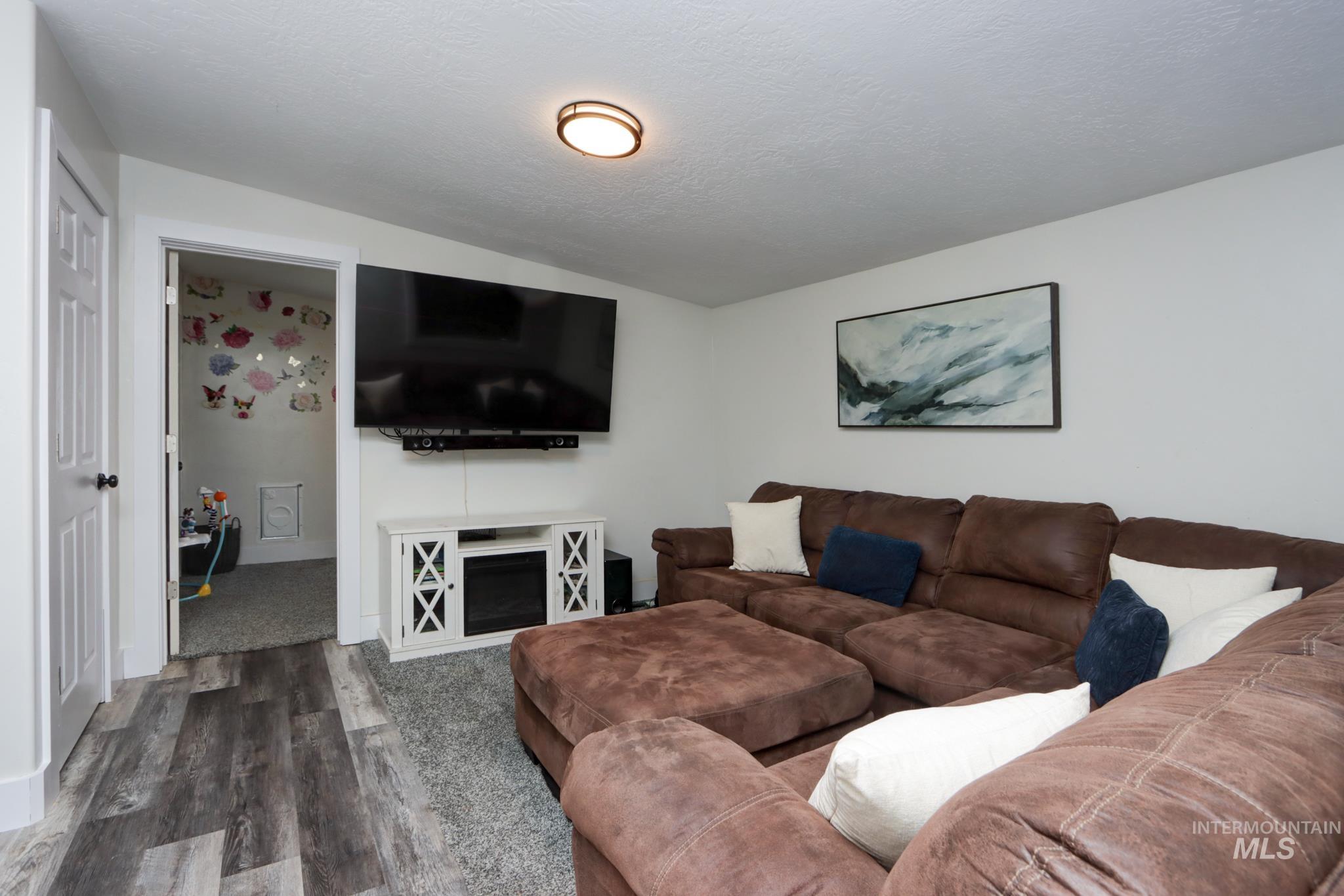 Living room featuring dark wood-type flooring, a textured ceiling, and vaulted ceiling
