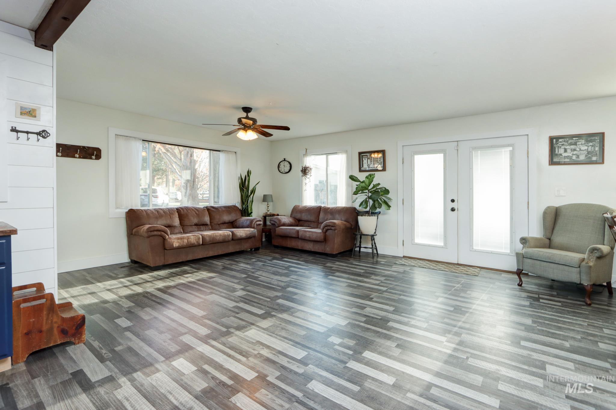 Living room with french doors, a ceiling fan, dark wood-style flooring, and beam ceiling