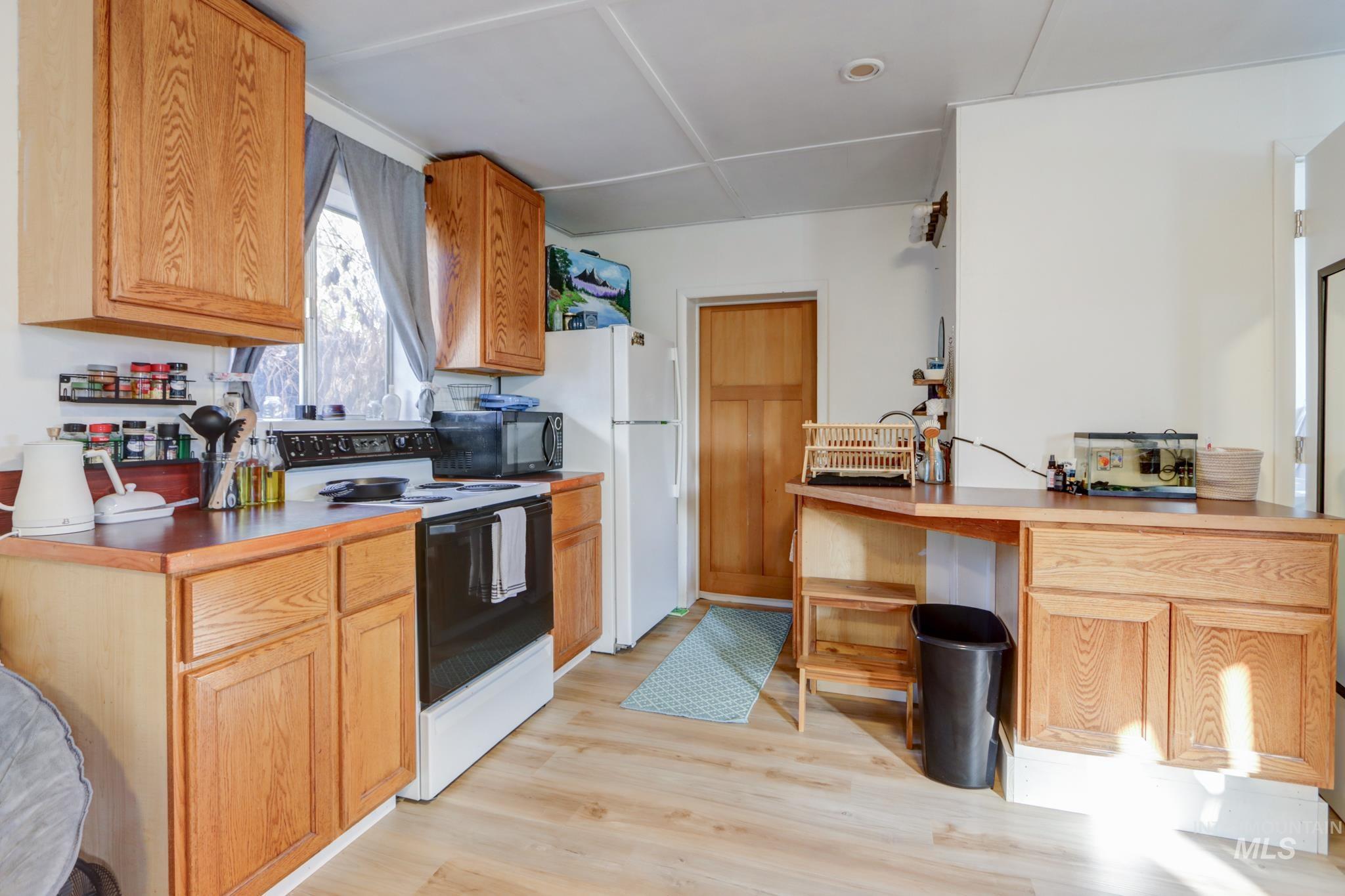 Kitchen featuring range with electric cooktop, light wood-style floors, a peninsula, black microwave, and light countertops