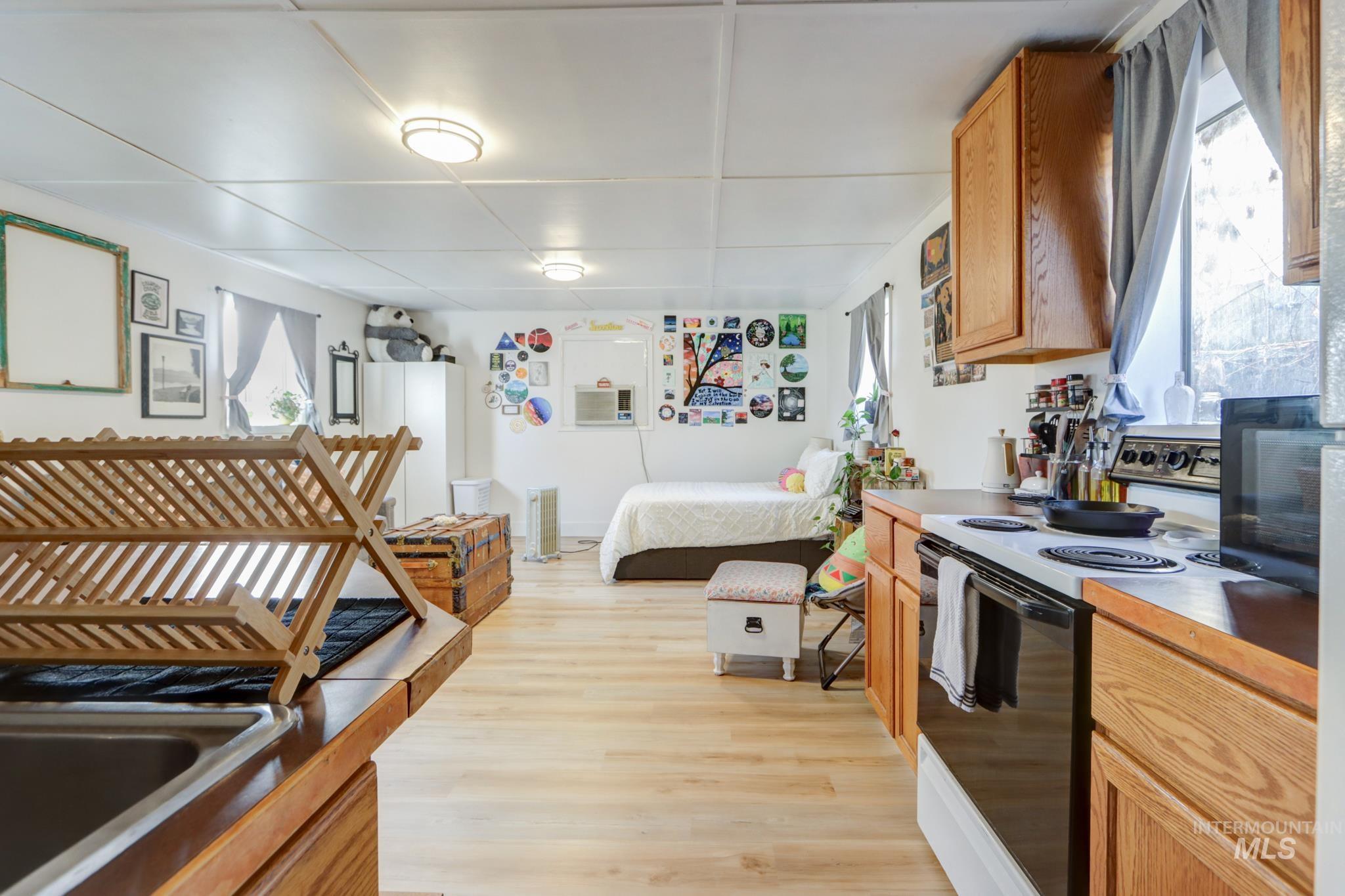 Kitchen featuring range with electric cooktop, light wood-style flooring, open floor plan, black microwave, and light countertops