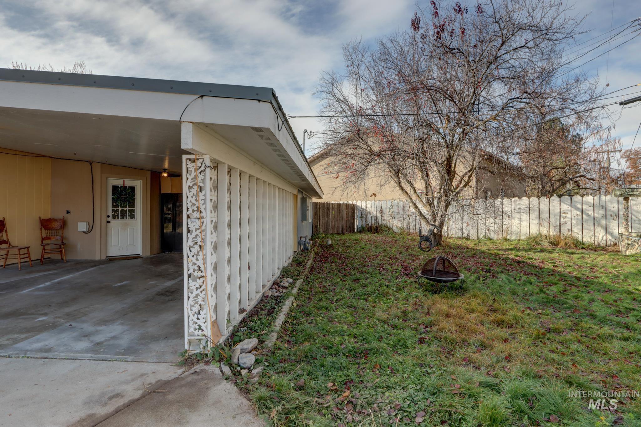 Fenced backyard with a carport, a fire pit, a patio area, and driveway