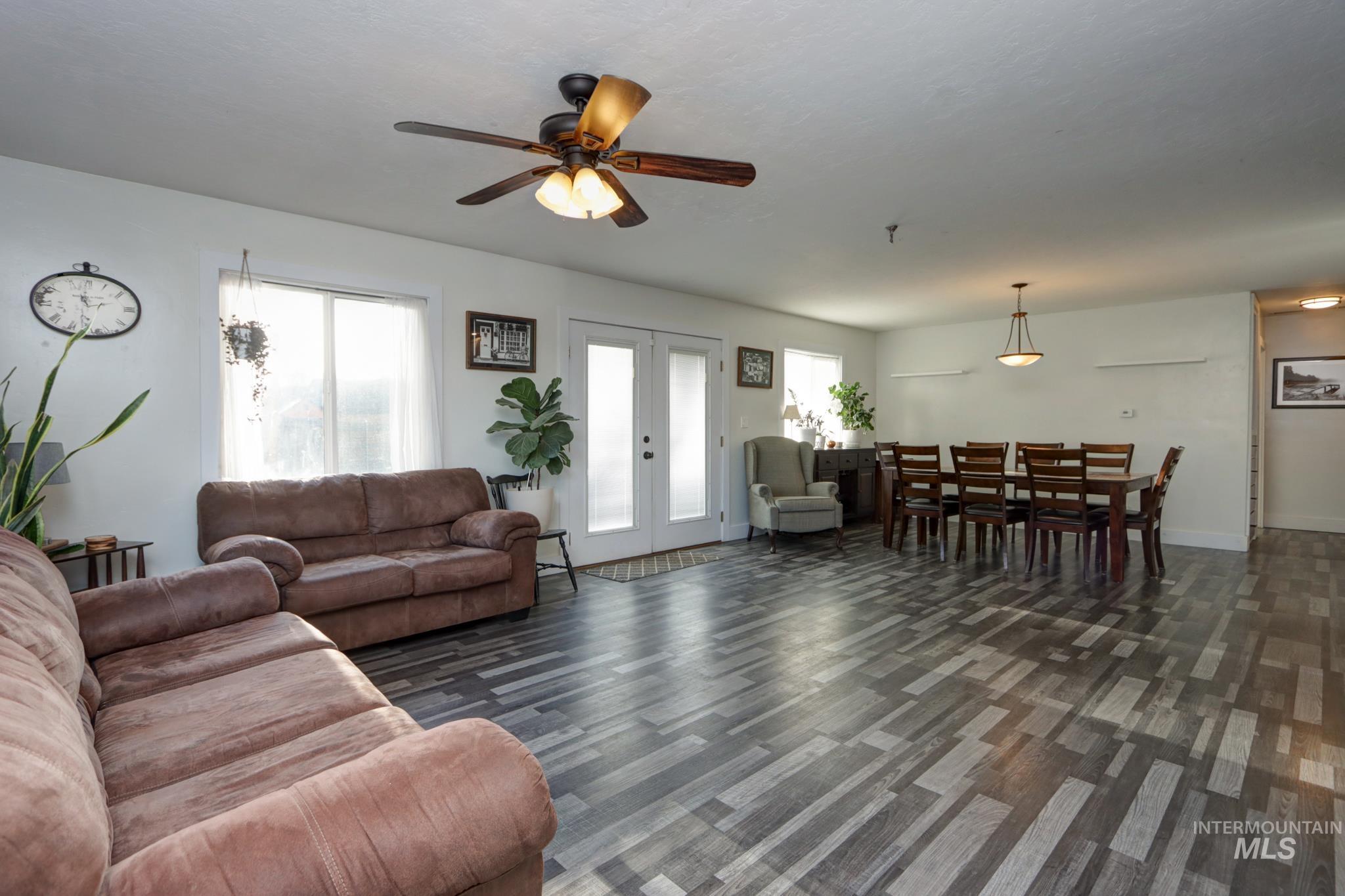 Living area featuring french doors, healthy amount of natural light, a ceiling fan, and dark wood-type flooring