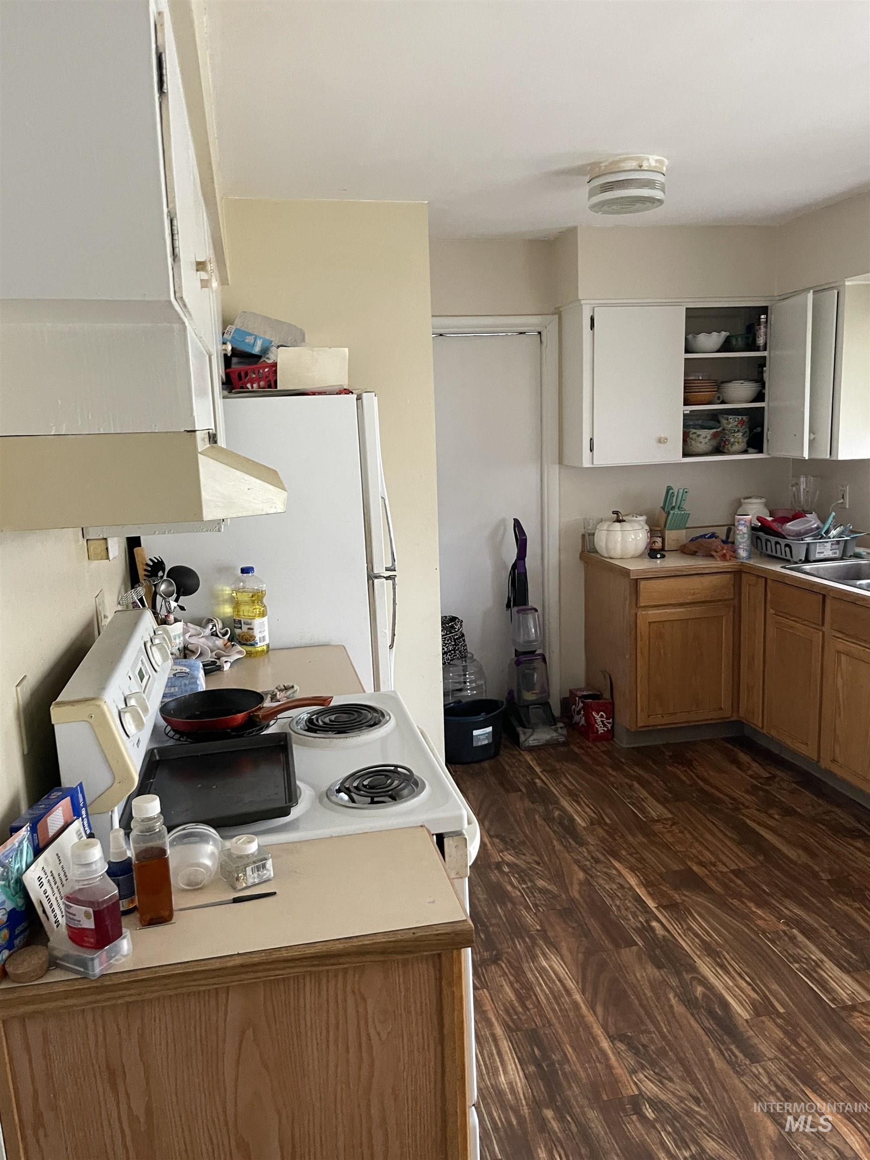 Kitchen featuring open shelves, light countertops, dark wood-style flooring, and white appliances
