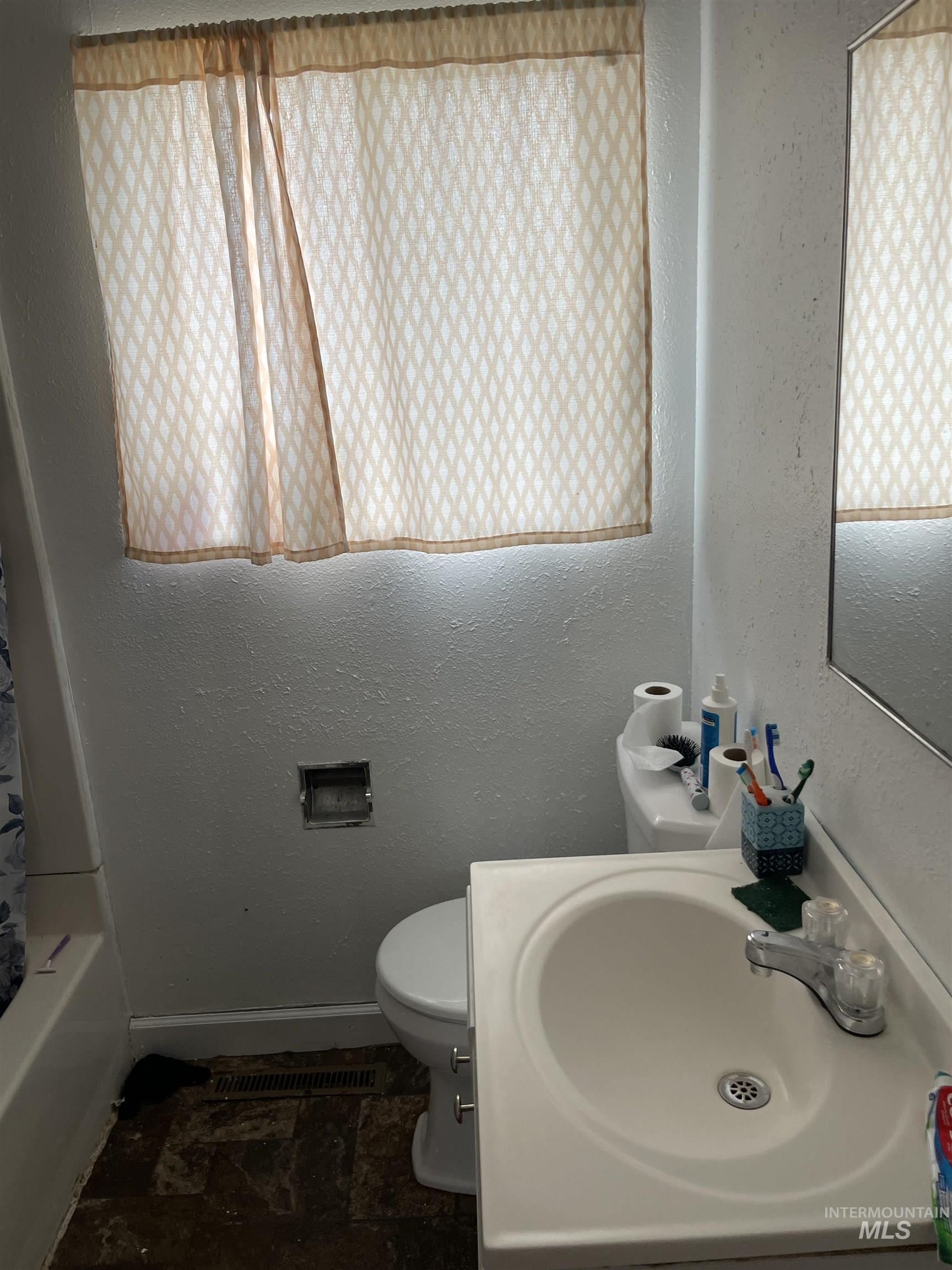 Full bathroom with a textured wall, vanity, and shower / bath combo