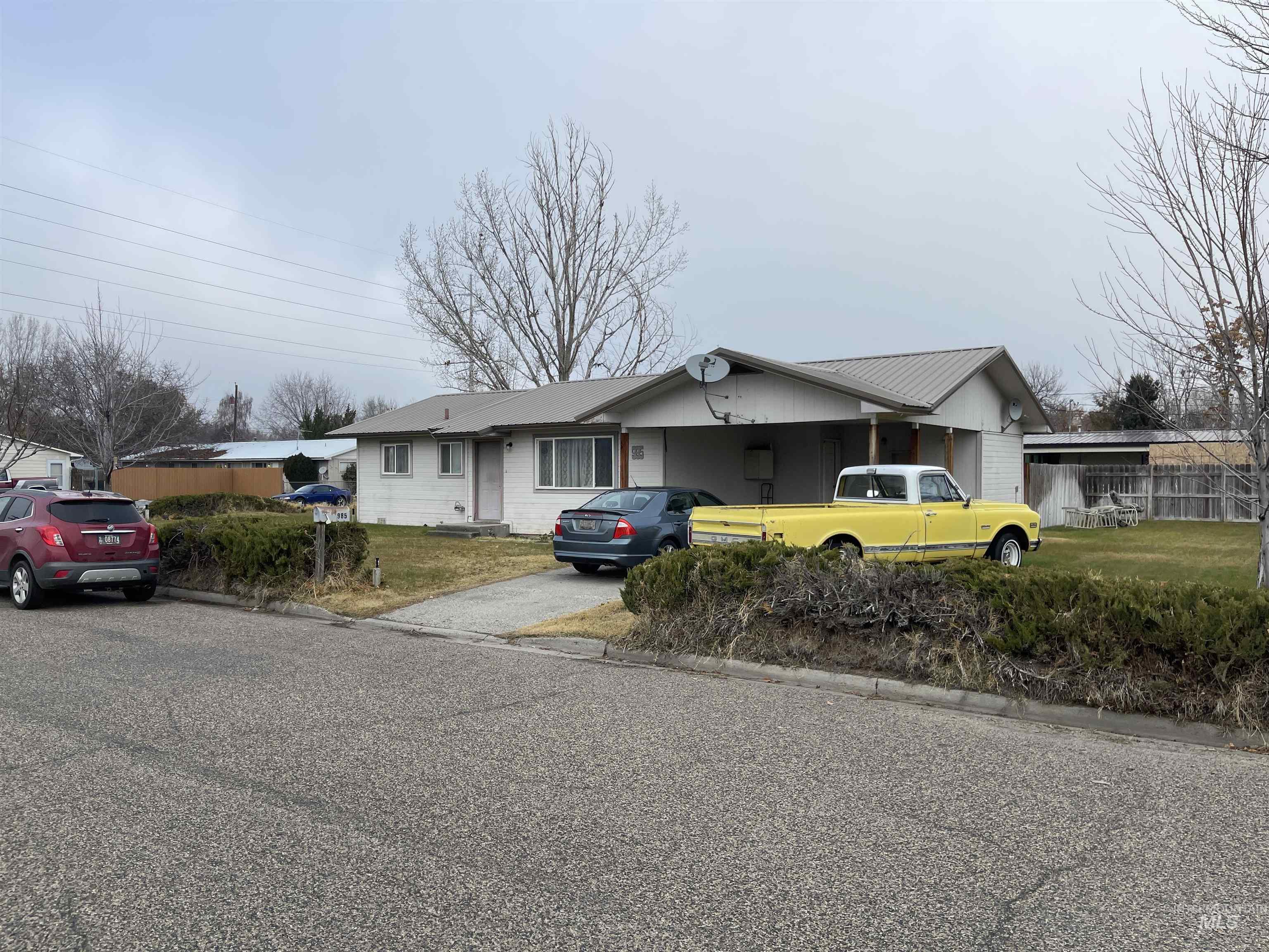 View of front facade with asphalt driveway and a front lawn