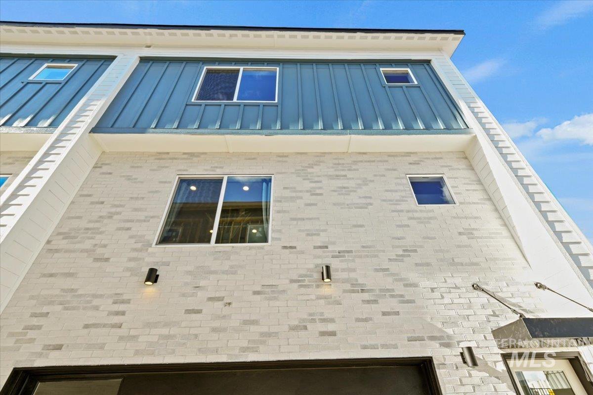 View of property exterior with a standing seam roof, a metal roof, and brick siding