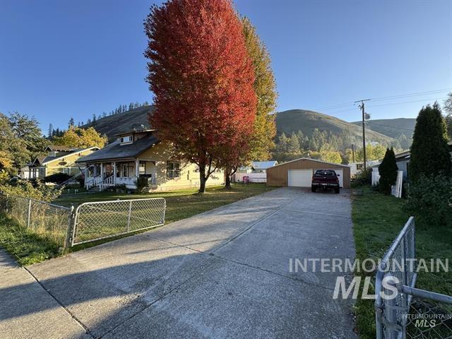 View of front of home with a detached garage, an outdoor structure, a mountain view, covered porch, and a gate