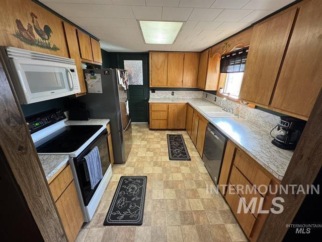 Kitchen featuring light countertops, electric range oven, brown cabinets, microwave, and dishwasher