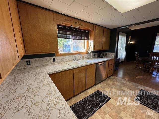 Kitchen featuring brown cabinets, plenty of natural light, and stainless steel dishwasher
