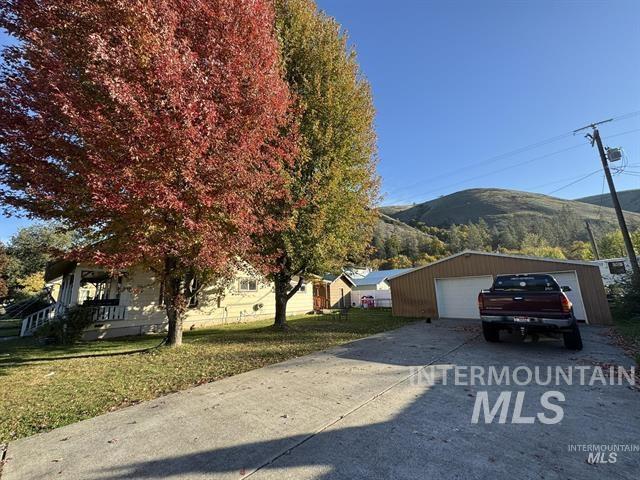 View of front of house with a mountain view, an outdoor structure, a detached garage, and a front lawn