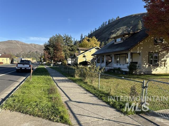 View of asphalt street featuring a mountain view, sidewalks, and curbs