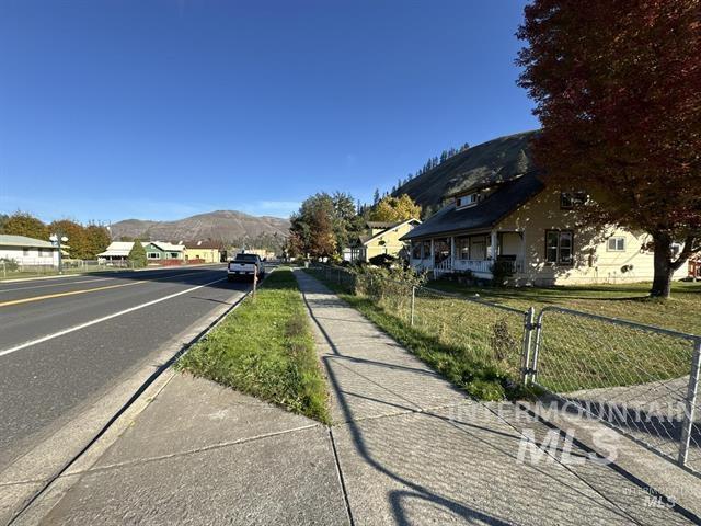 View of asphalt street featuring a mountain view and sidewalks