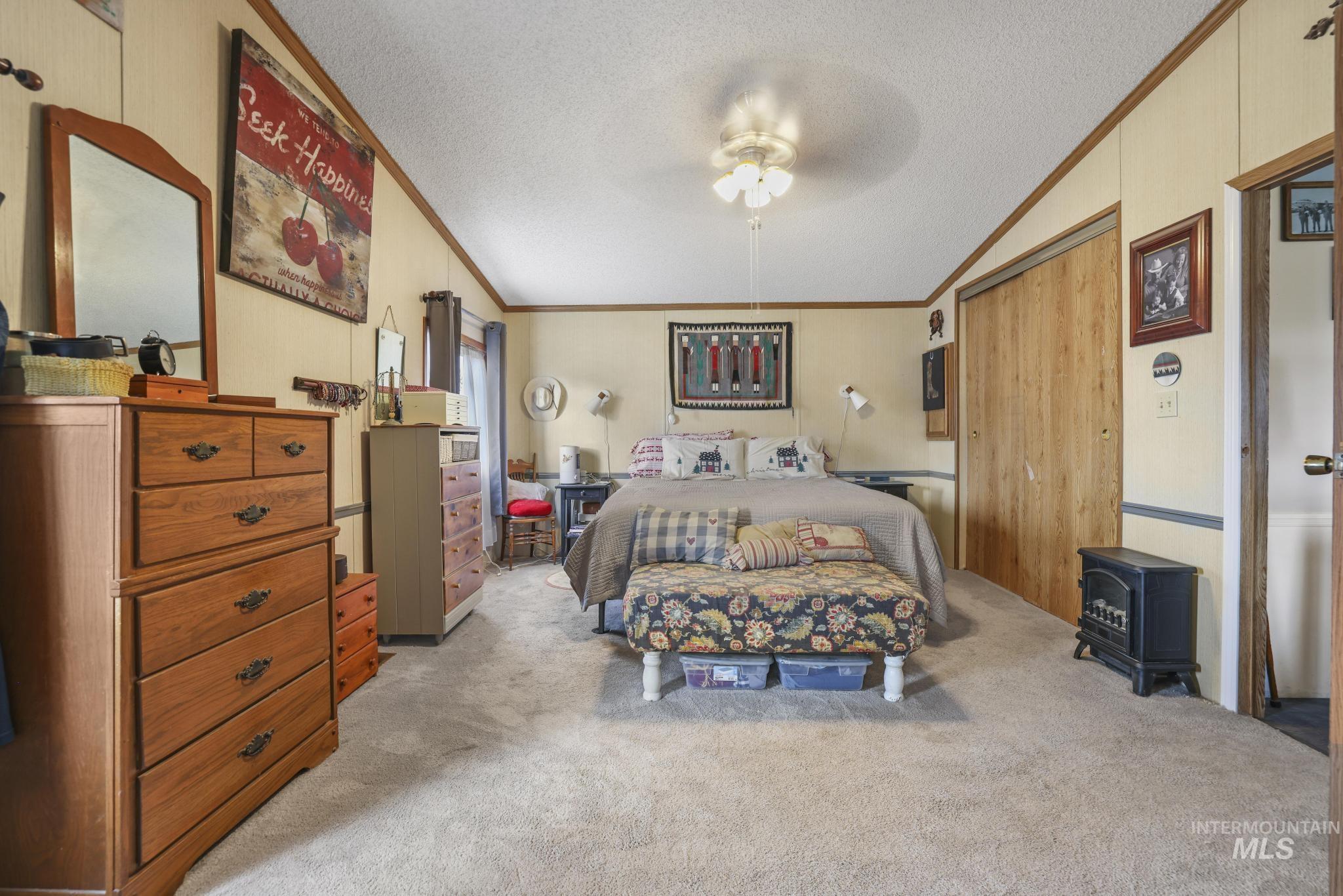 Bedroom featuring ornamental molding, carpet, a textured ceiling, and a ceiling fan