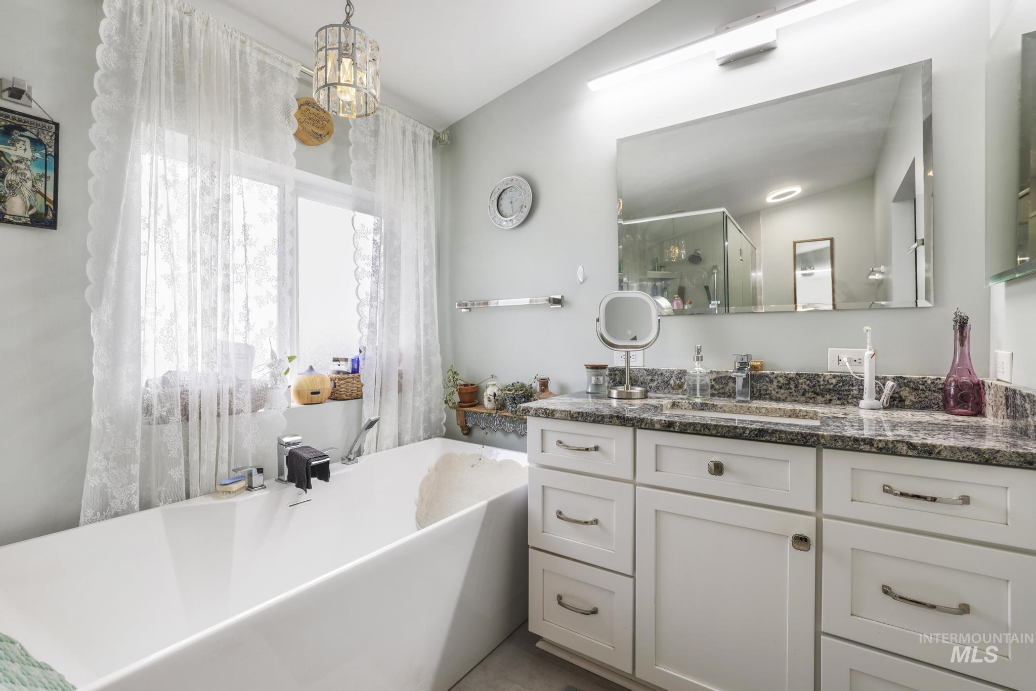 Bathroom with vanity, a soaking tub, and a stall shower