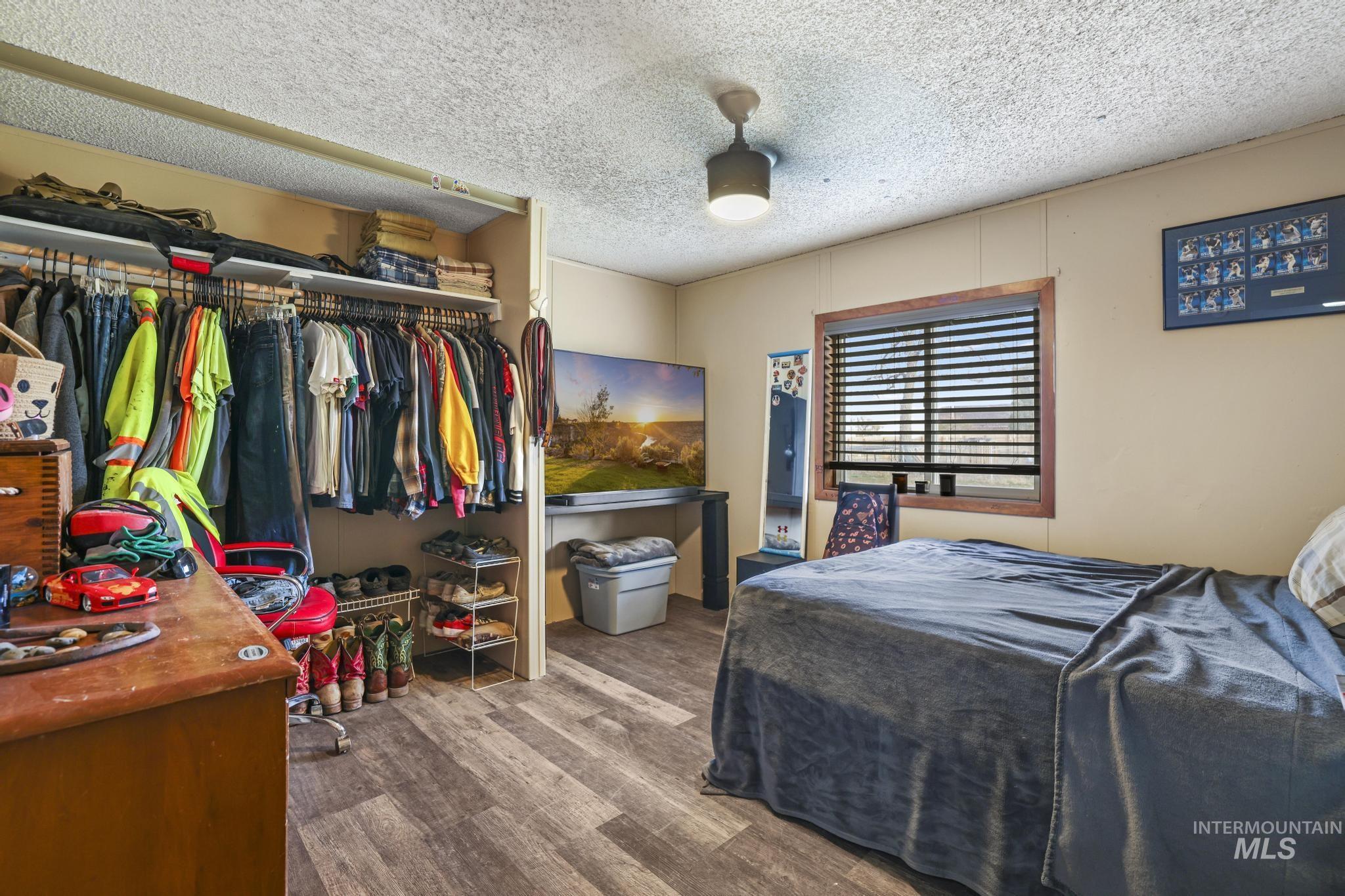 Bedroom with wood finished floors, a textured ceiling, and a closet