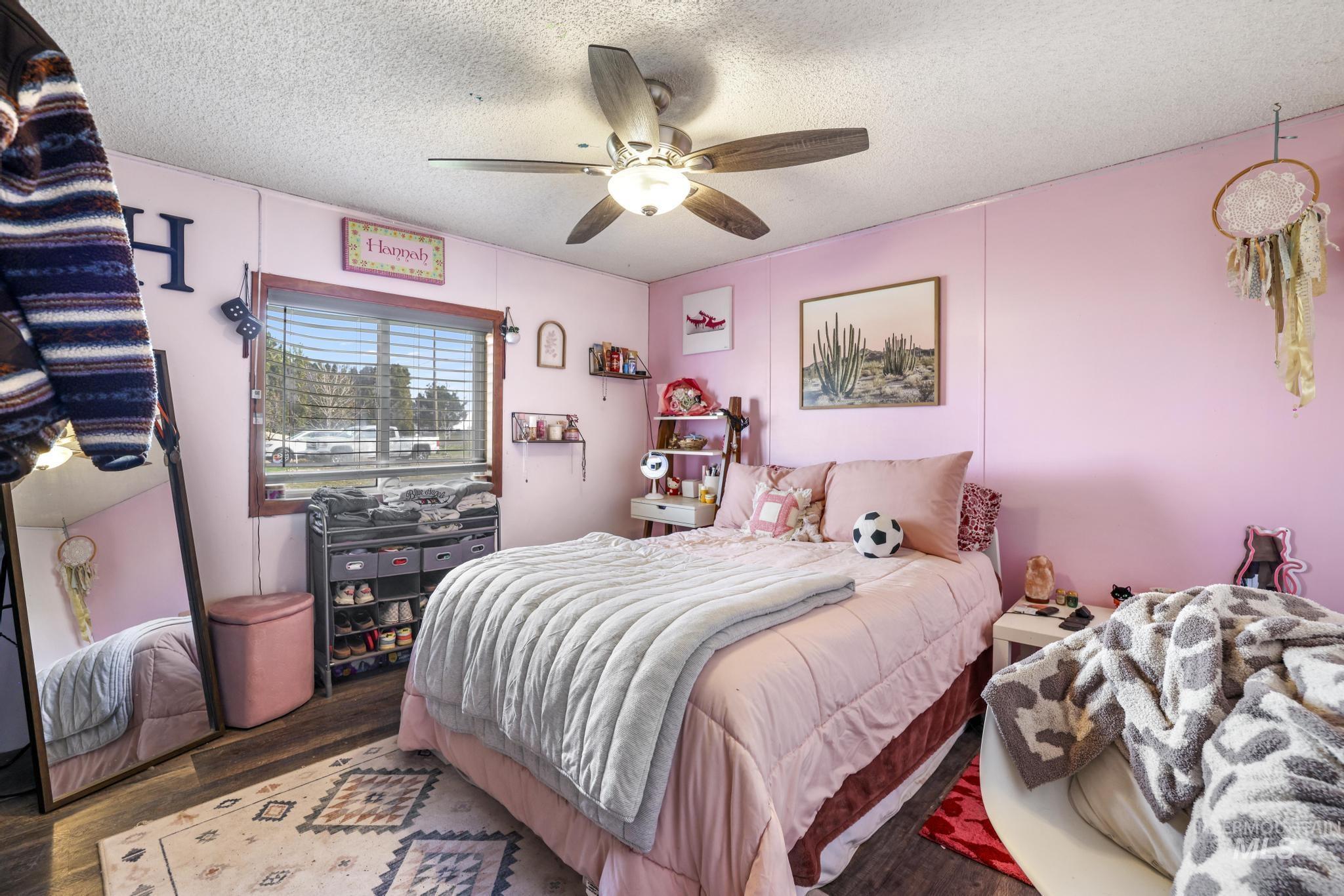 Bedroom featuring wood finished floors, a textured ceiling, and a ceiling fan