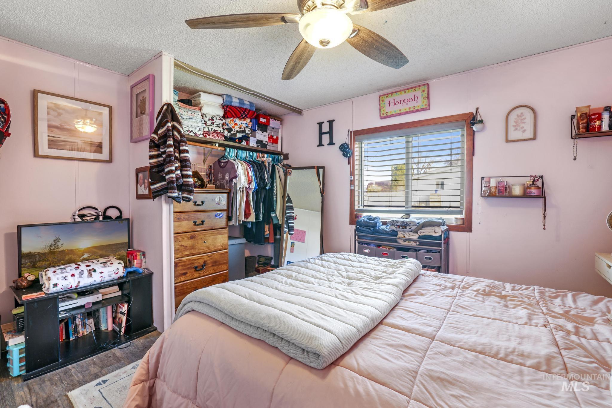 Bedroom with a textured ceiling, wood finished floors, a closet, and ceiling fan