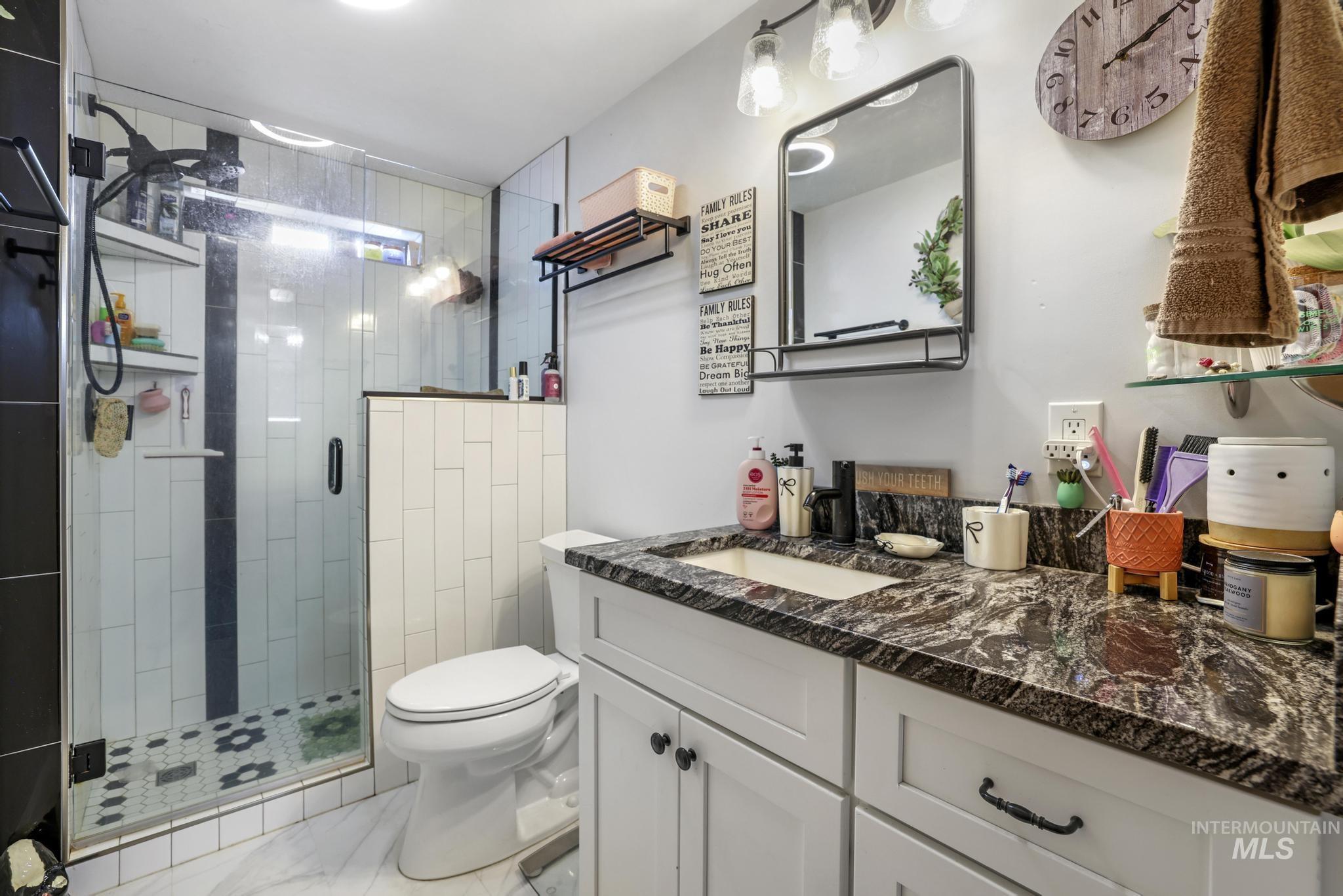 Bathroom with vanity, a stall shower, and light marble finish floors