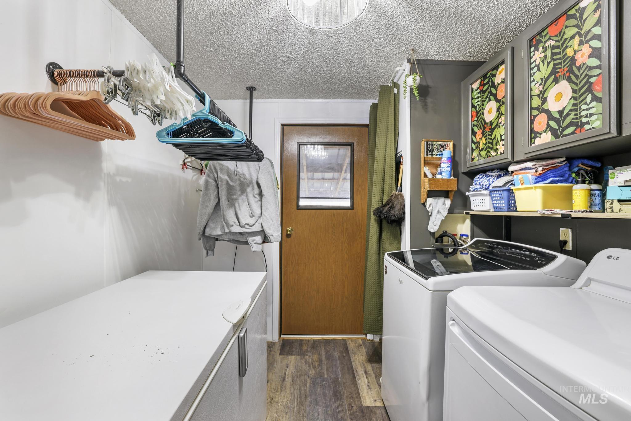 Laundry area featuring a textured ceiling, washing machine and dryer, and cabinet space