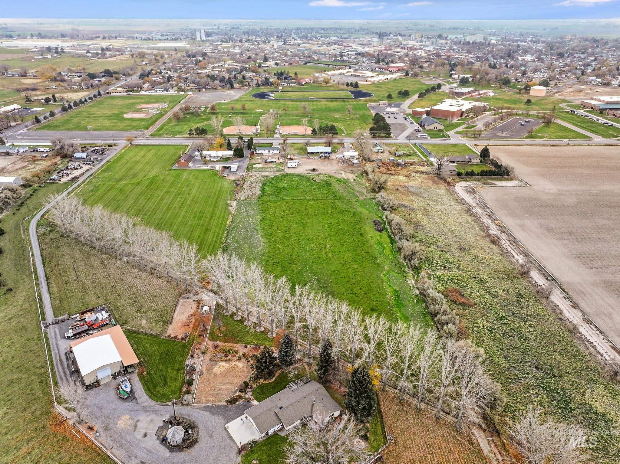 Aerial view of property and surrounding area featuring rural landscape and rows of crops