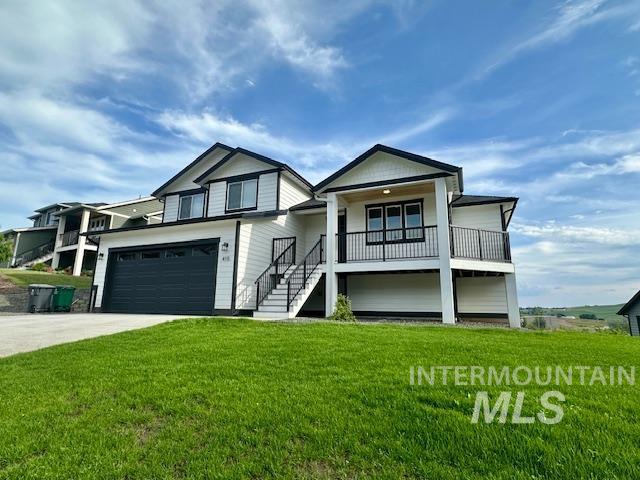 View of front of house with driveway, a front yard, stairs, and a garage