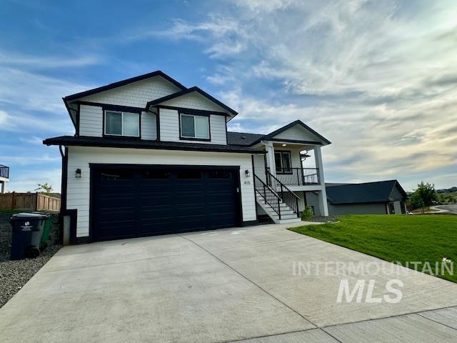 View of front facade with an attached garage, concrete driveway, stairs, and covered porch