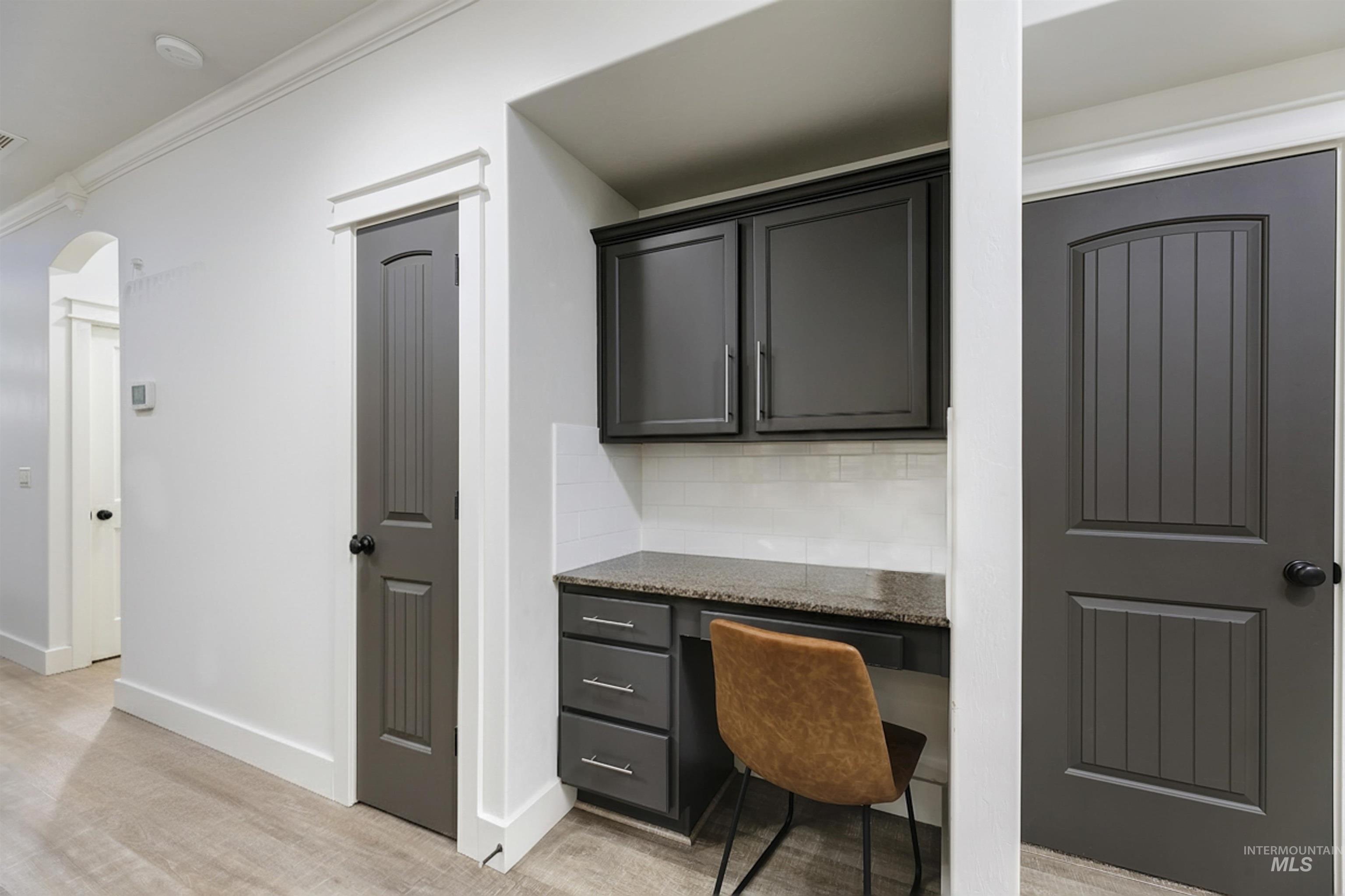 This built-in desk area offers a convenient space for work, studying, or staying organized. With extra cabinets, under stair storage, and a coat closet it adds both functionality and storage.