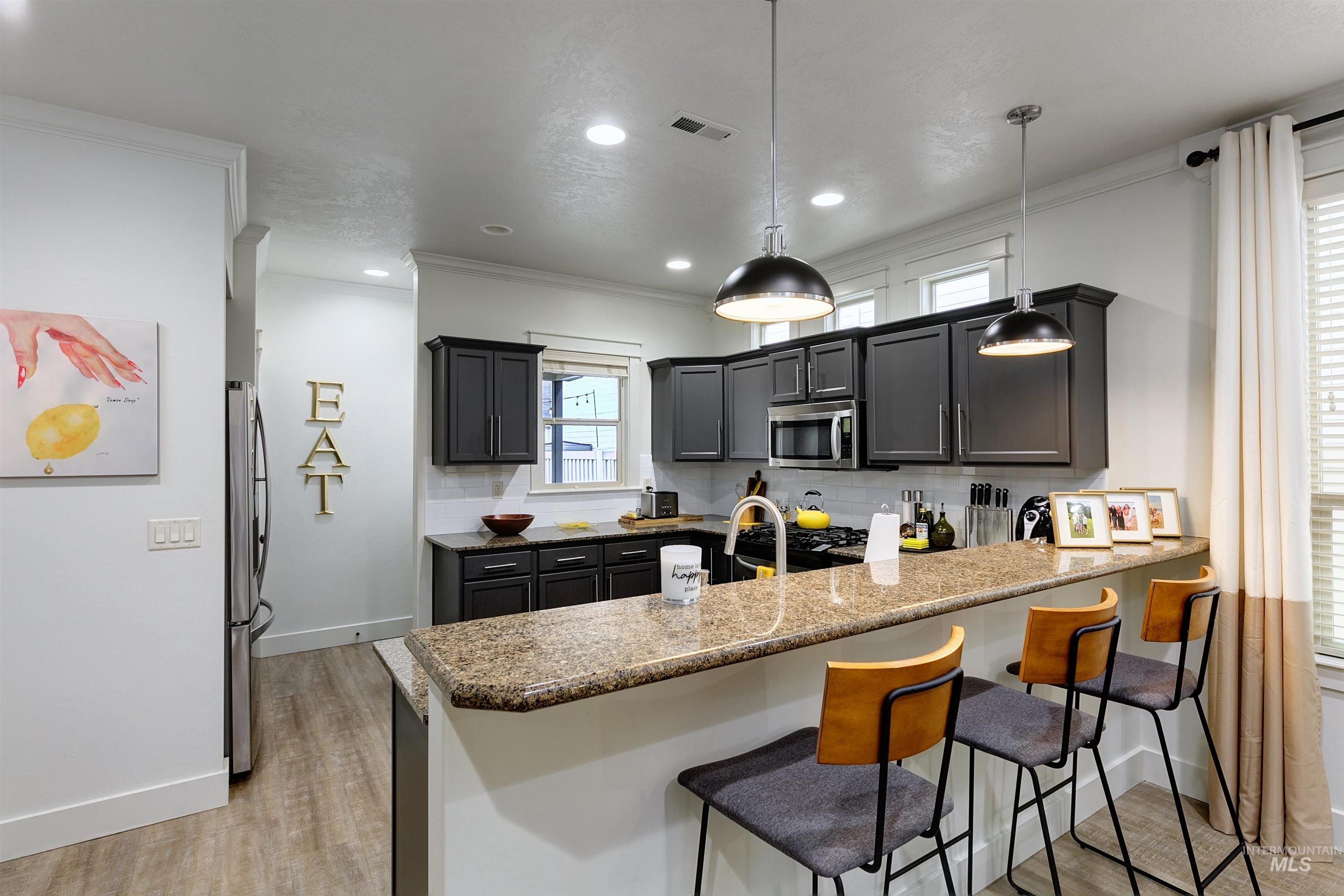 Kitchen with a breakfast bar area, granite counters, pendant lighting, and an open layout