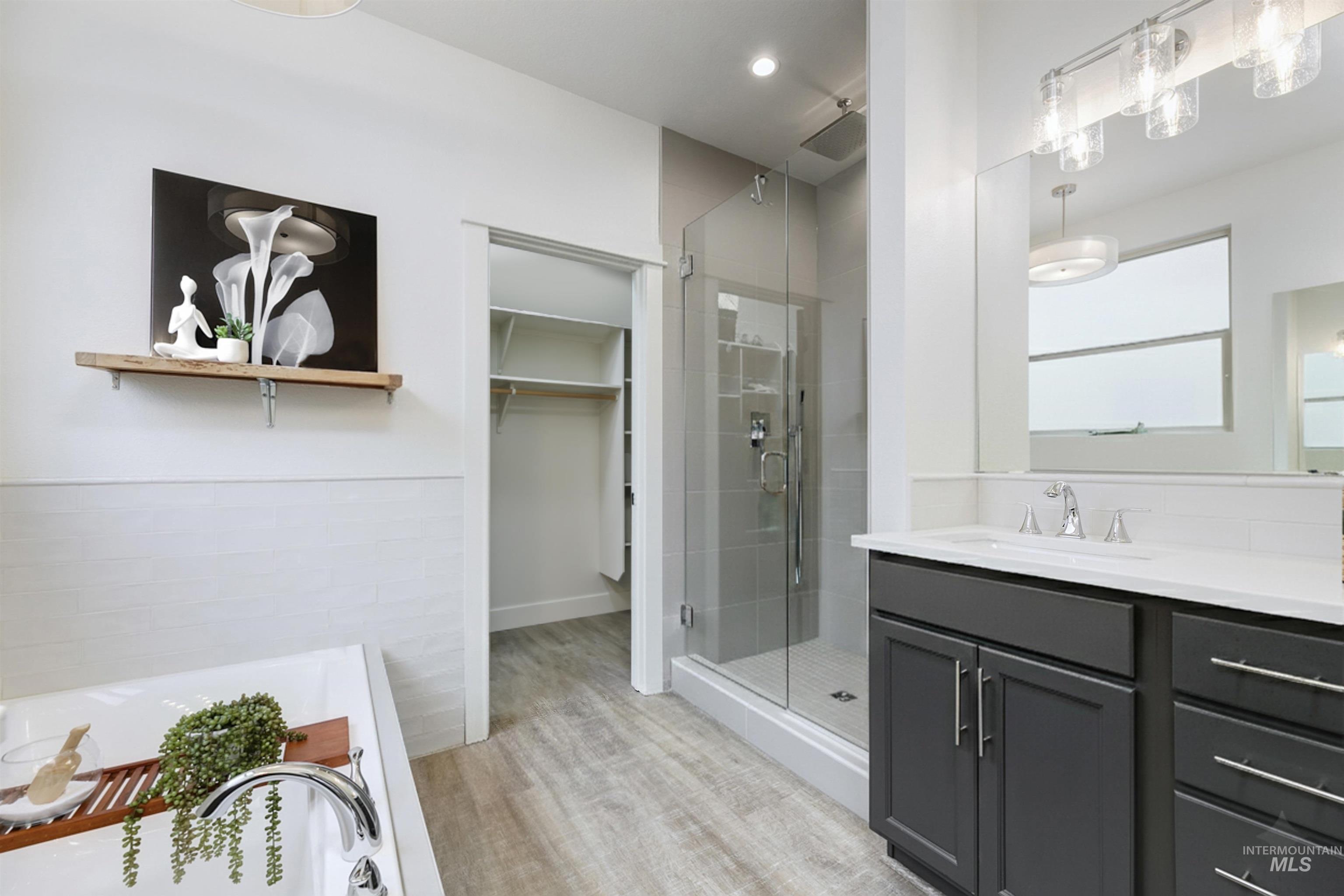 Bathroom featuring a vanity, luxurious walk in shower, deep soaking tub, and a walk in closet. Bright and clean finishes.