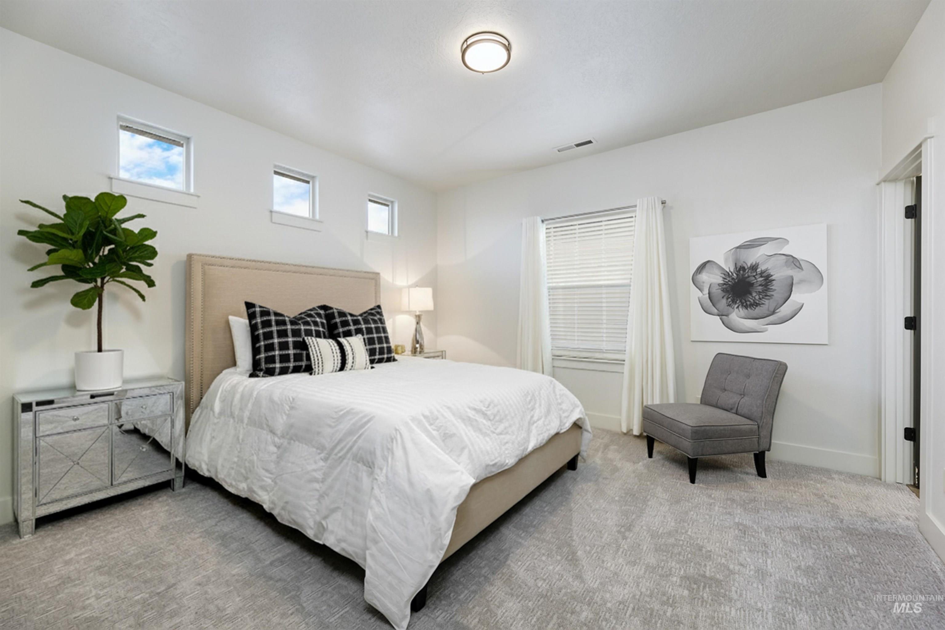 Fully furnished guest bedroom has warm carpet, ample natural light, a closet and is connected to a Jack and Jill bathroom.