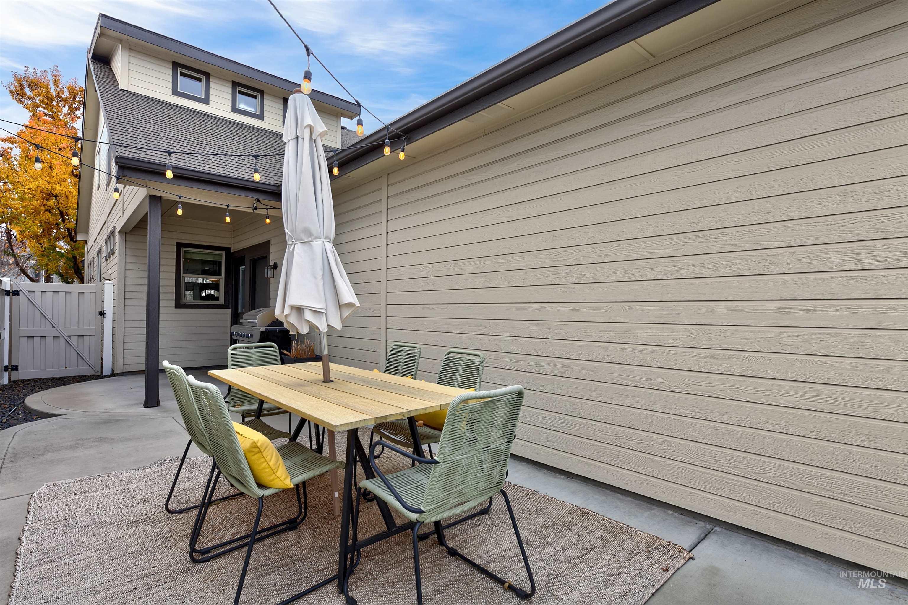 Back patio with string lights, access to garage and kitchen. With room to personalize and enjoy year-round.