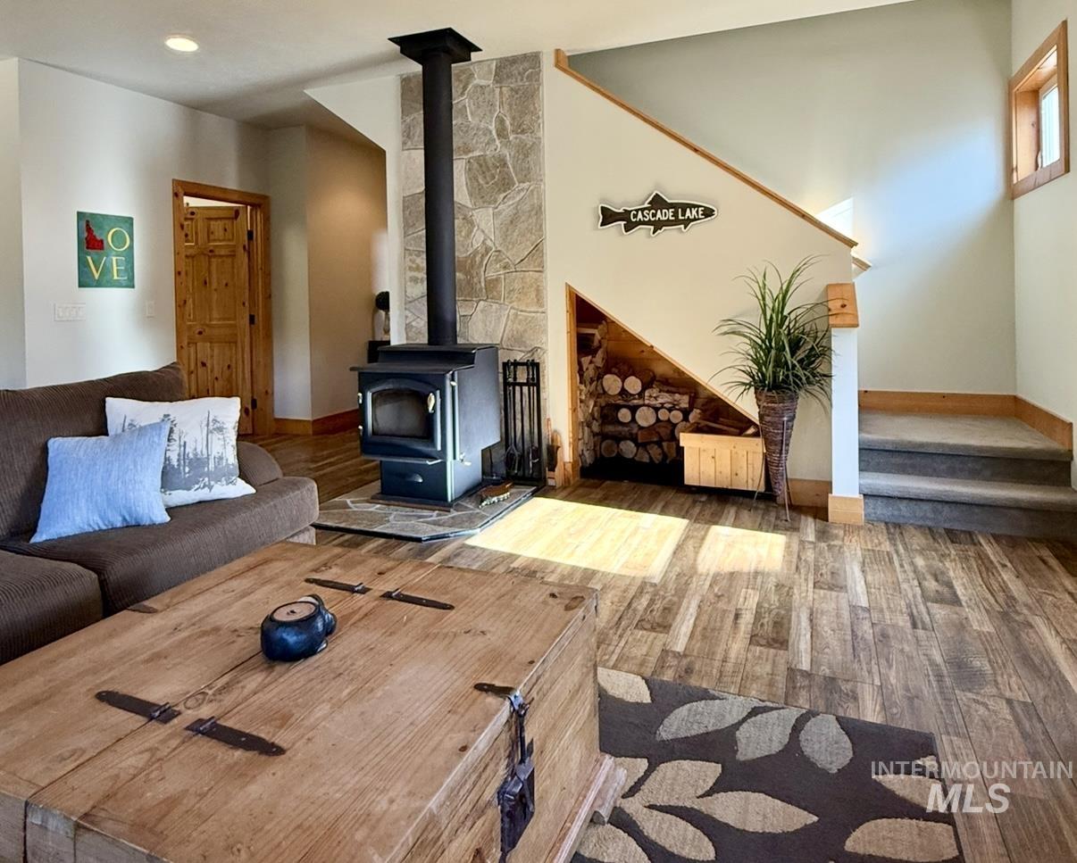 Living area featuring a wood stove, stairs, wood finished floors, and recessed lighting