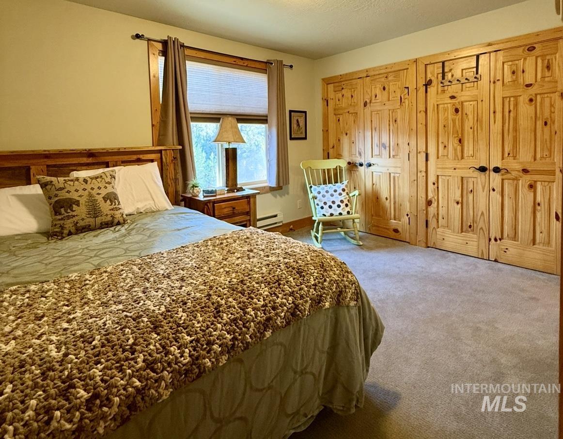 Carpeted bedroom featuring a closet, a textured ceiling, and a baseboard heating unit