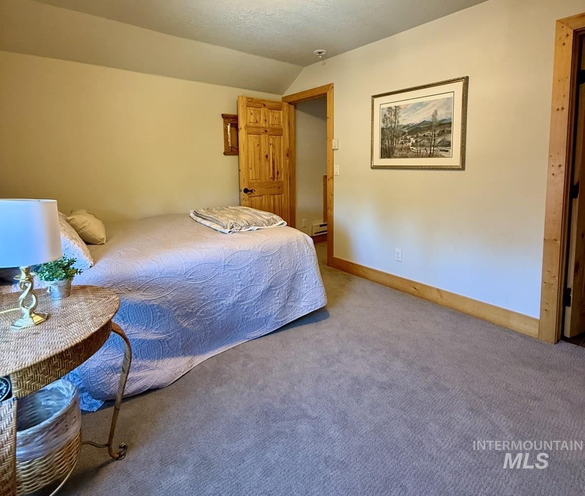Bedroom with lofted ceiling, carpet, and a textured ceiling