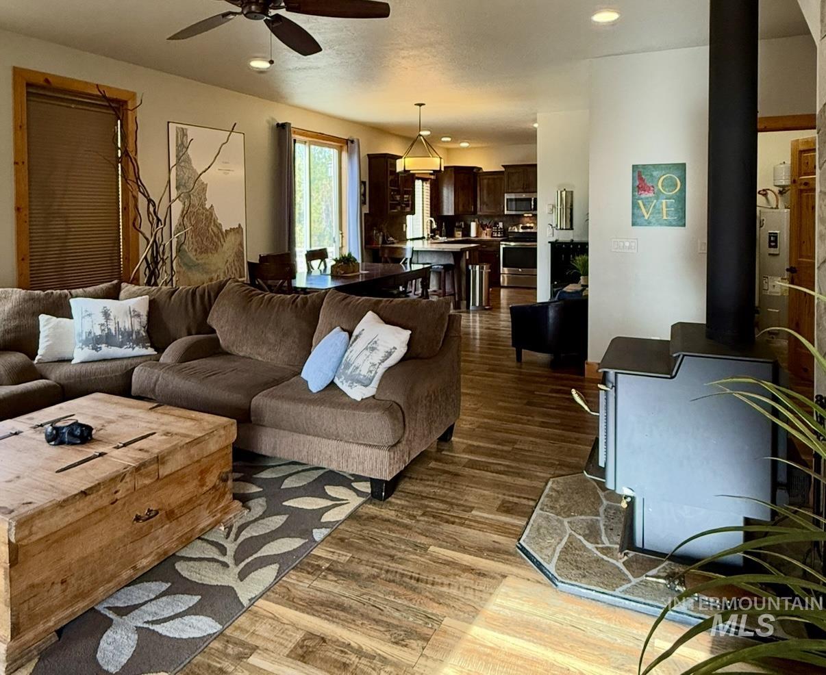 Living area featuring a wood stove, light wood-style flooring, a ceiling fan, and recessed lighting