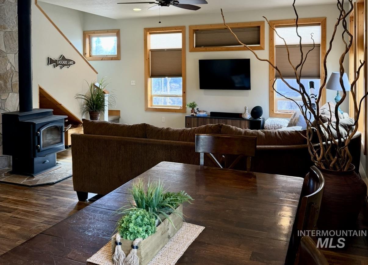Living room featuring a wood stove, a ceiling fan, and dark wood-style floors
