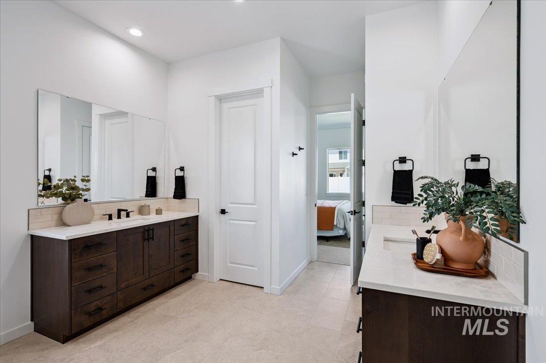 Bathroom featuring decorative backsplash, two vanities, connected bathroom, and recessed lighting