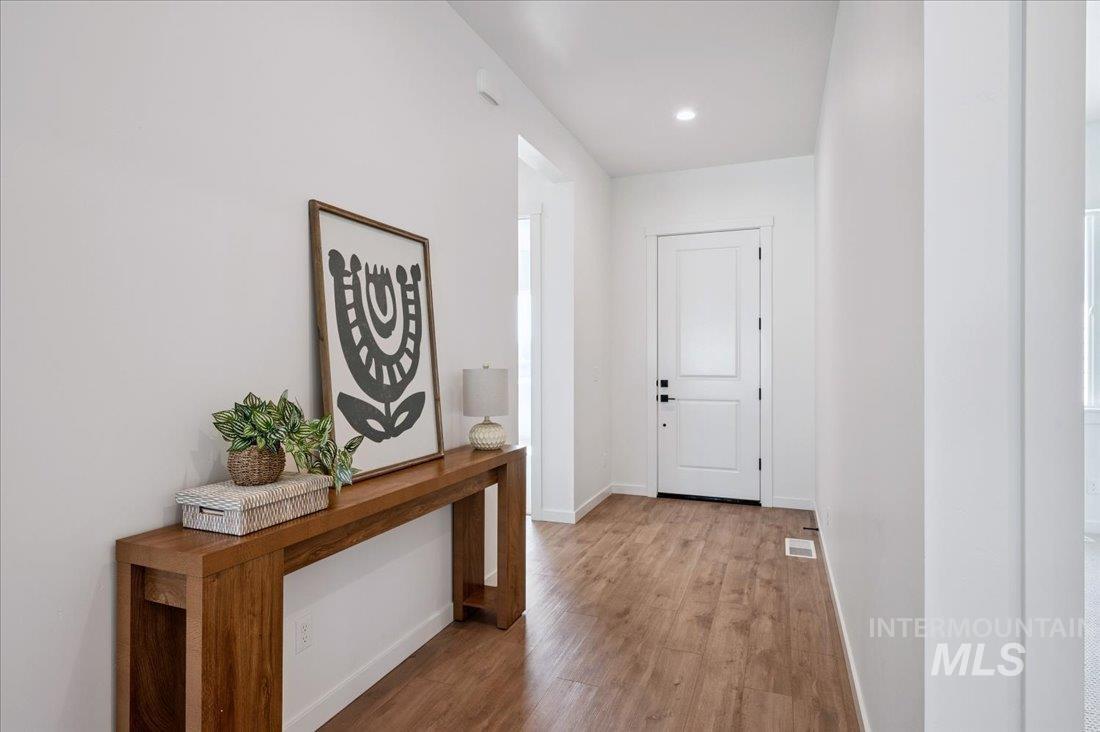 Hallway with light wood finished floors and recessed lighting