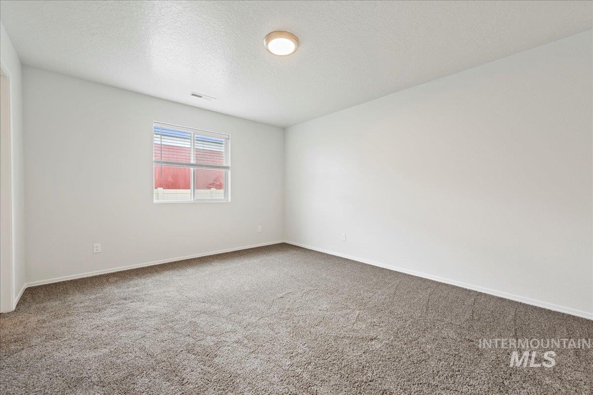 Empty room featuring a textured ceiling and carpet