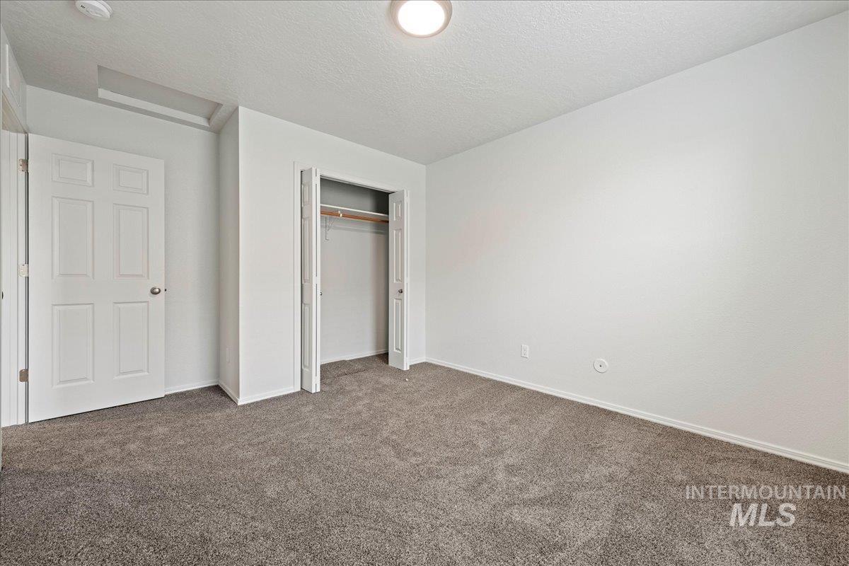 Unfurnished bedroom featuring a textured ceiling, a closet, and carpet floors