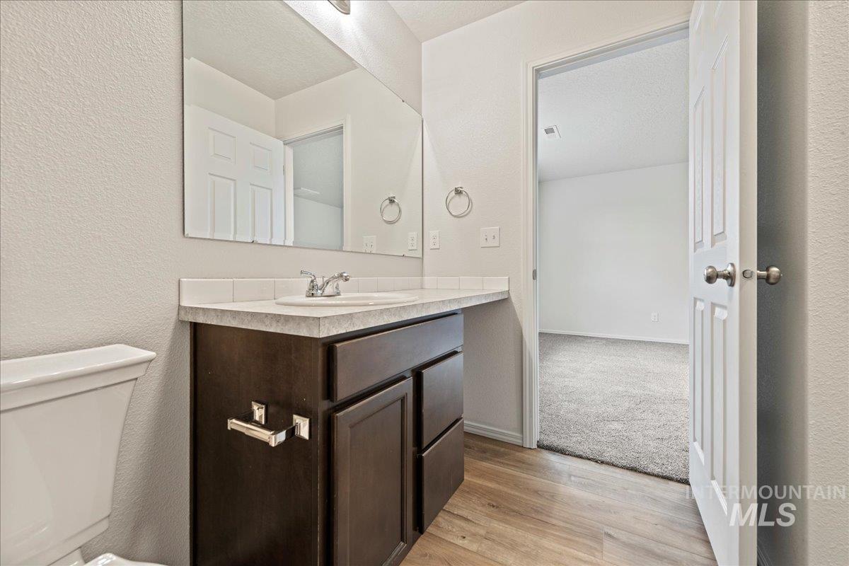 Bathroom with a textured wall, vanity, light wood-type flooring, and a textured ceiling