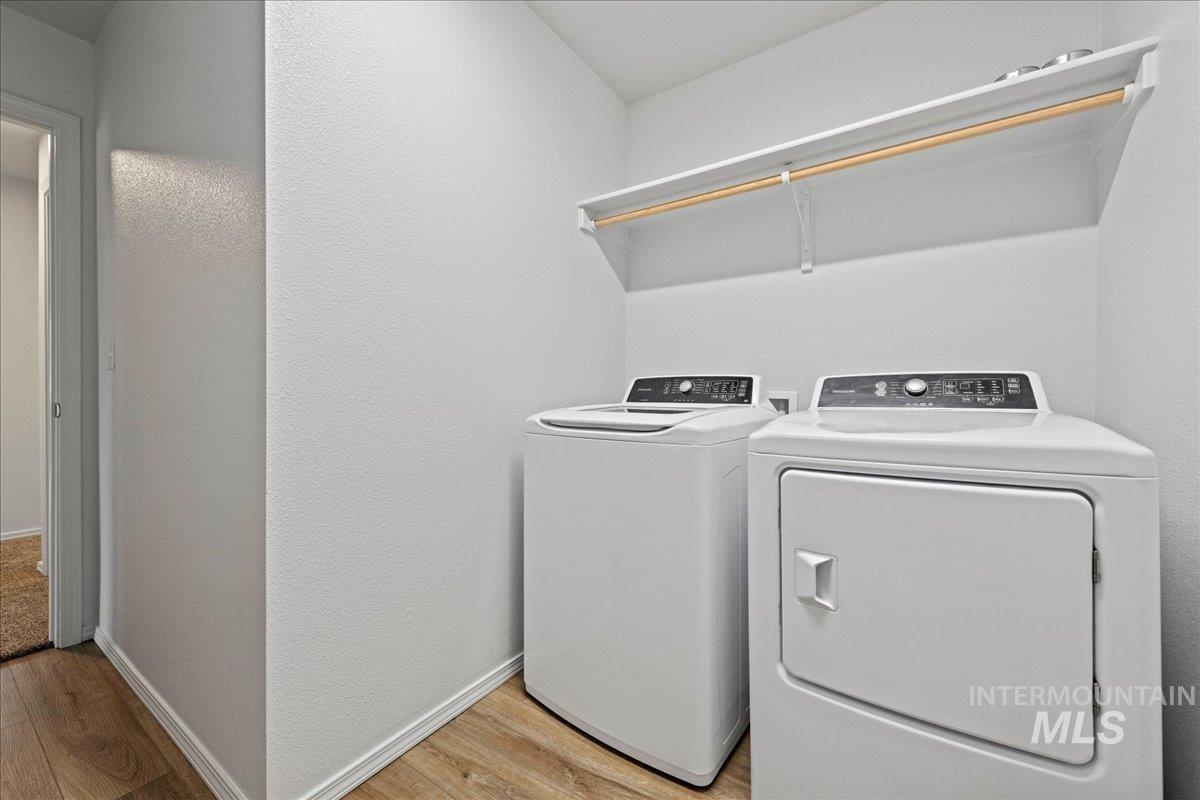 Washroom featuring light wood-style floors, washer and dryer, and a textured wall