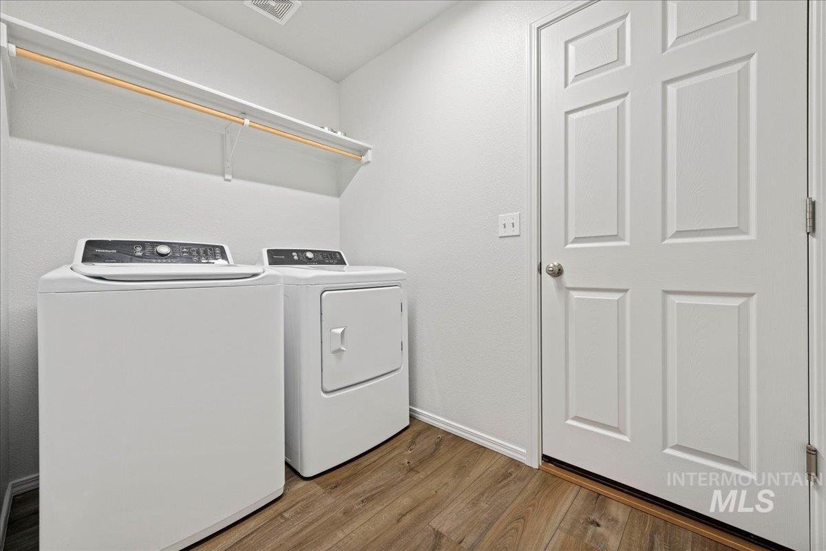 Laundry room with wood finished floors and independent washer and dryer